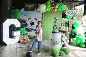 Green and white balloon arrangement with soccer-themed decorations and large letter display.
