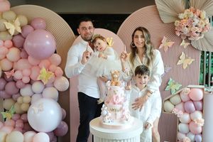 Elegant birthday party setup with pink balloon arch and butterfly decorations.