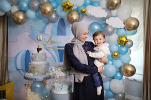 Blue and gold themed party setup featuring cloud decorations and balloon garlands.