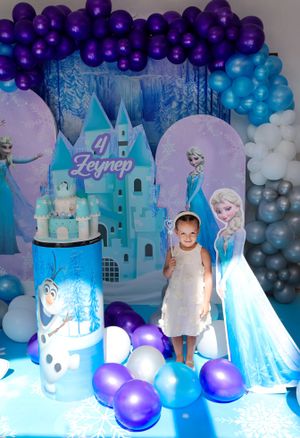 Blue and purple balloon-decorated party setup with castle cake and snowy theme.