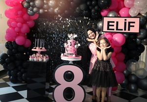 8th birthday celebration with sparkly backdrop and pink and black balloon decorations.