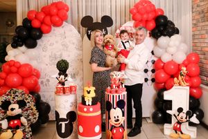 Family gathering at a Mickey Mouse themed birthday party with festive red and black decorations.