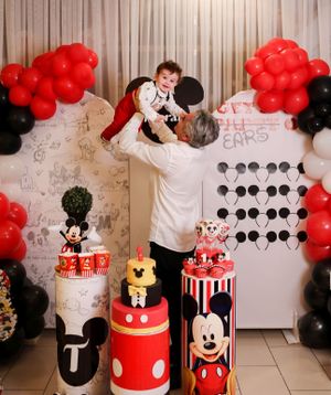 Mickey Mouse themed birthday party with red and black balloon decorations and themed cakes.