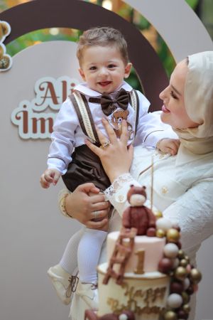 Celebratory moment with formal attire and teddy bear themed cake decoration.