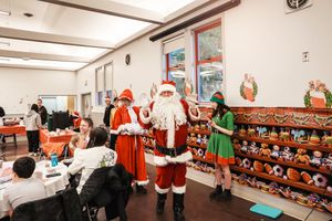 Holiday figures stand near shelves of festive decorations in a cafeteria setting during a seasonal celebration.