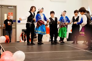 Students in traditional costumes gather in a hallway with balloons during a school performance or cultural event.