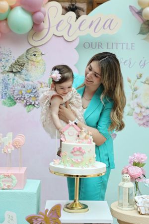 Pastel-themed birthday celebration with floral decorations and soft pink cake display.