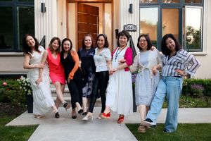 A group of friends pose together on a front porch, dressed in summer casual attire in white, red, and blue outfits.