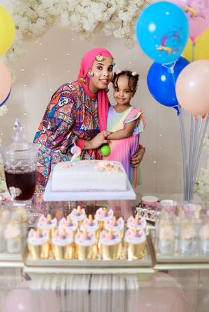 Festive birthday party setup with colorful balloons and cupcake display on dessert table.