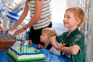 A birthday celebration with a decorated blue cake and balloon decorations at a festive party.