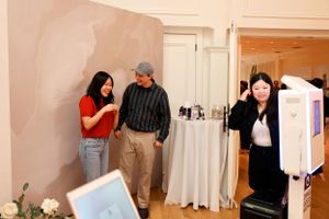 People chatting in a room with white draped walls and studio equipment.