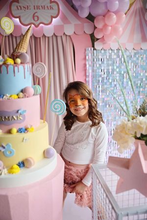 Whimsical birthday party setup with tall tiered cake and pink balloon decorations.