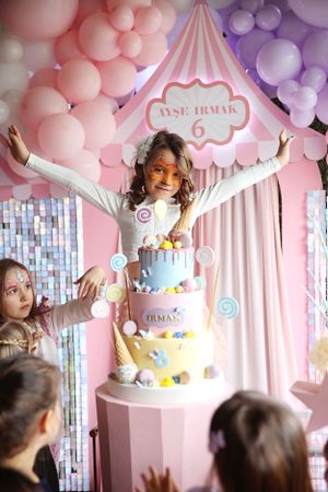 Birthday celebration with a three-tiered cake and balloon decorations in pink and purple.
