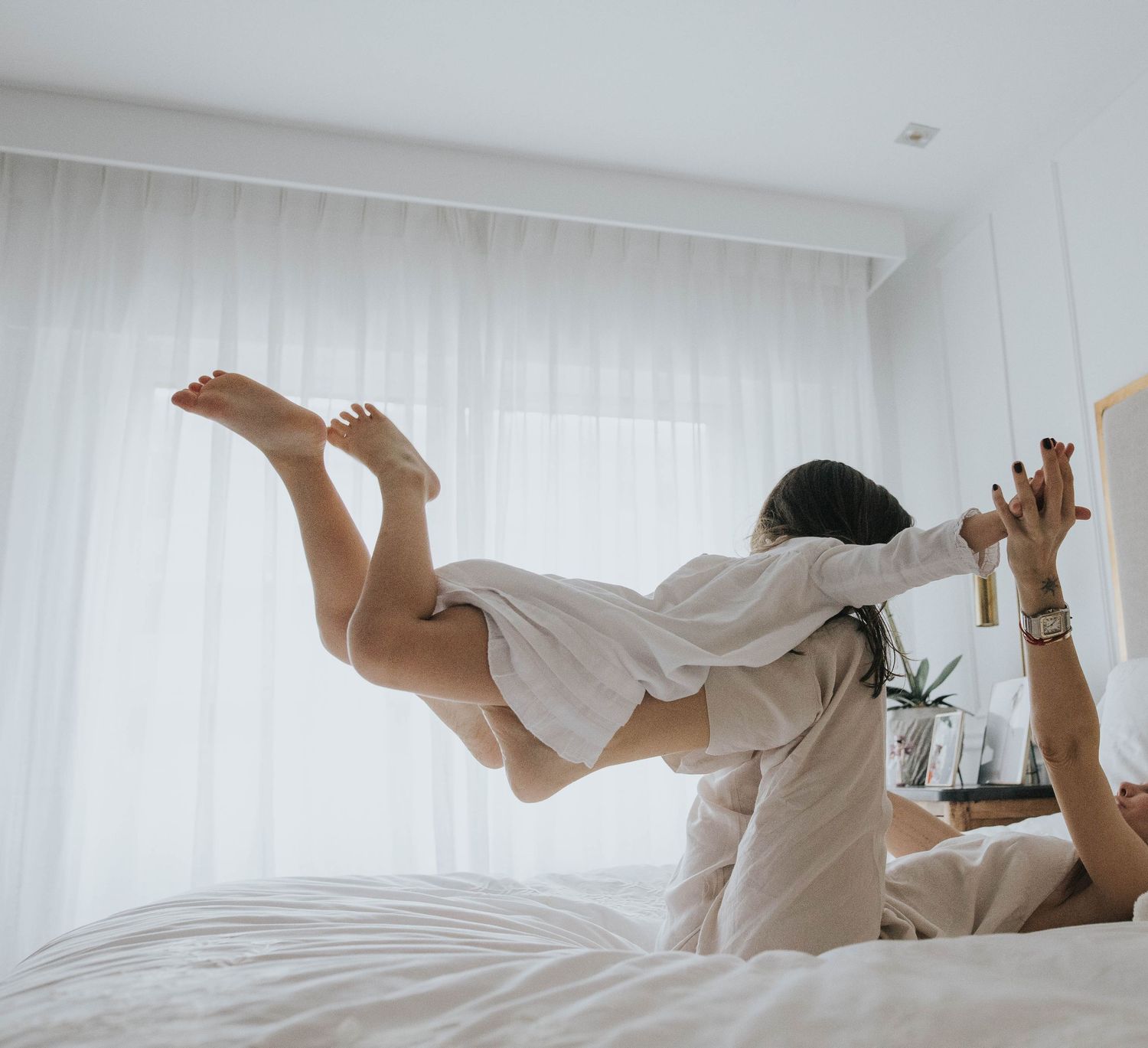 cuando volar en las piernas de mamá era volar de verdad. madre y hija jugando en la cama. momentos sencillos de la vida
