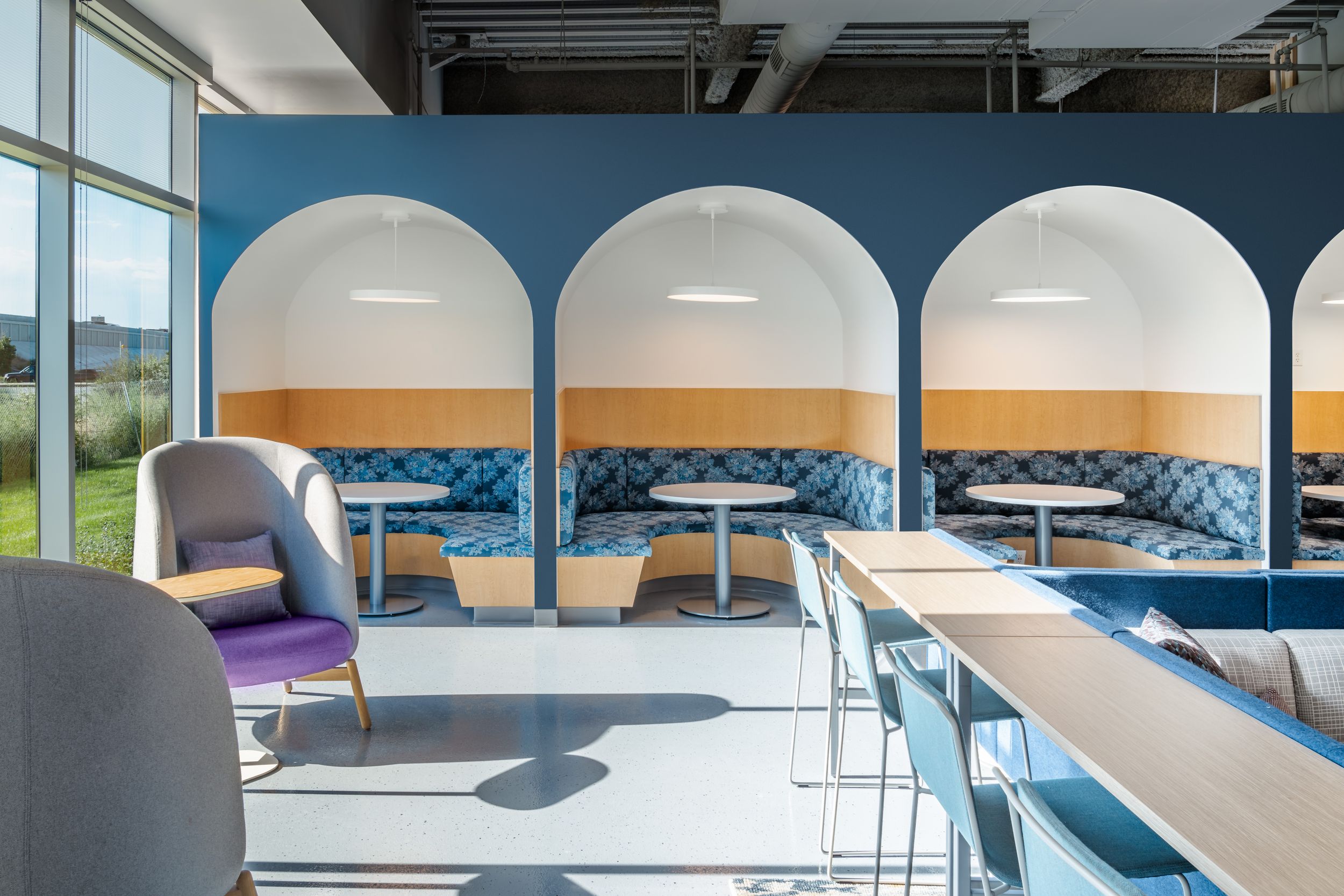 Modern office interior with rows of sleek white desks and large windows illuminating the open workspace.