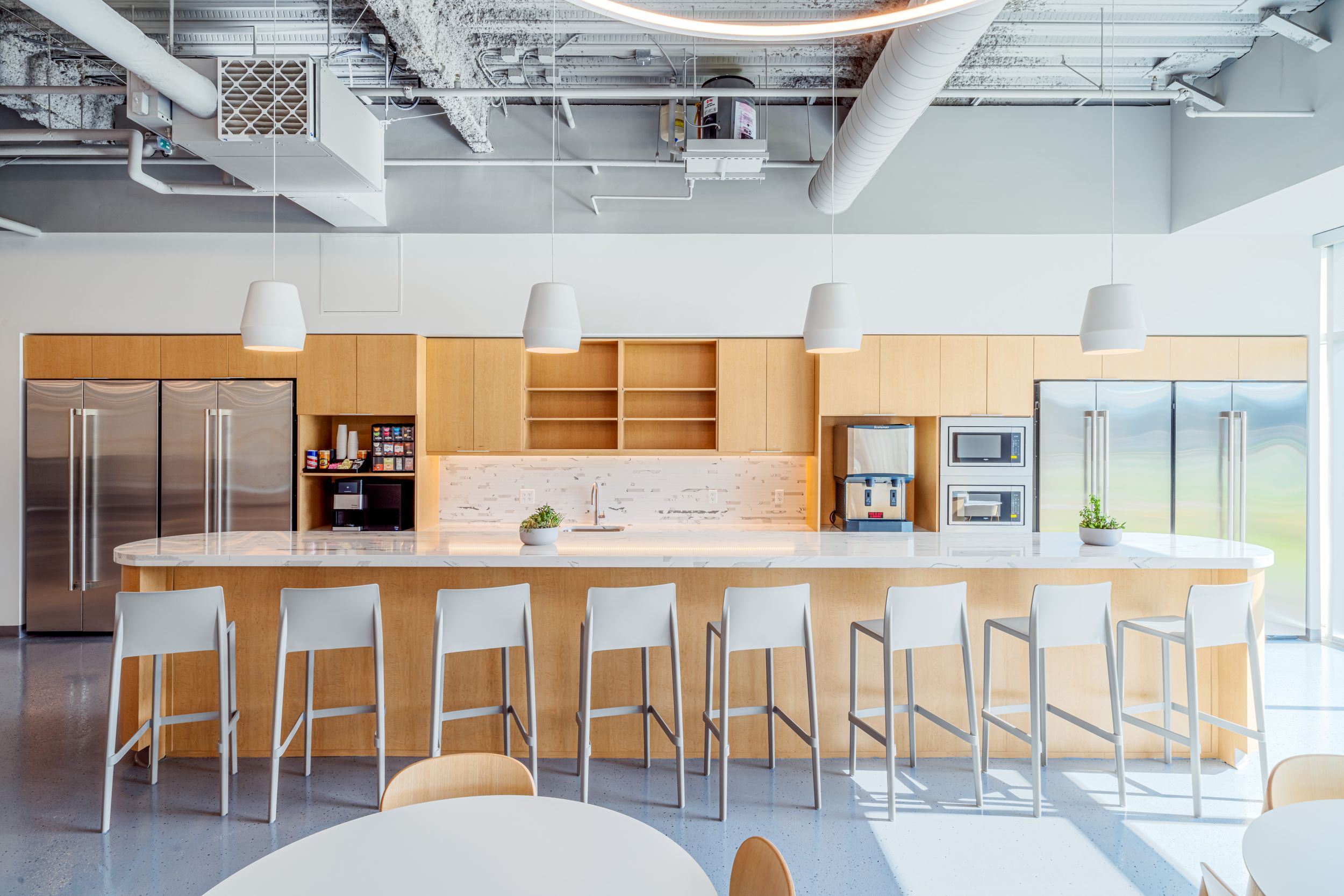 Minimalist office space with white desks, wood accents, and wall-mounted storage cabinets in a bright modern interior.