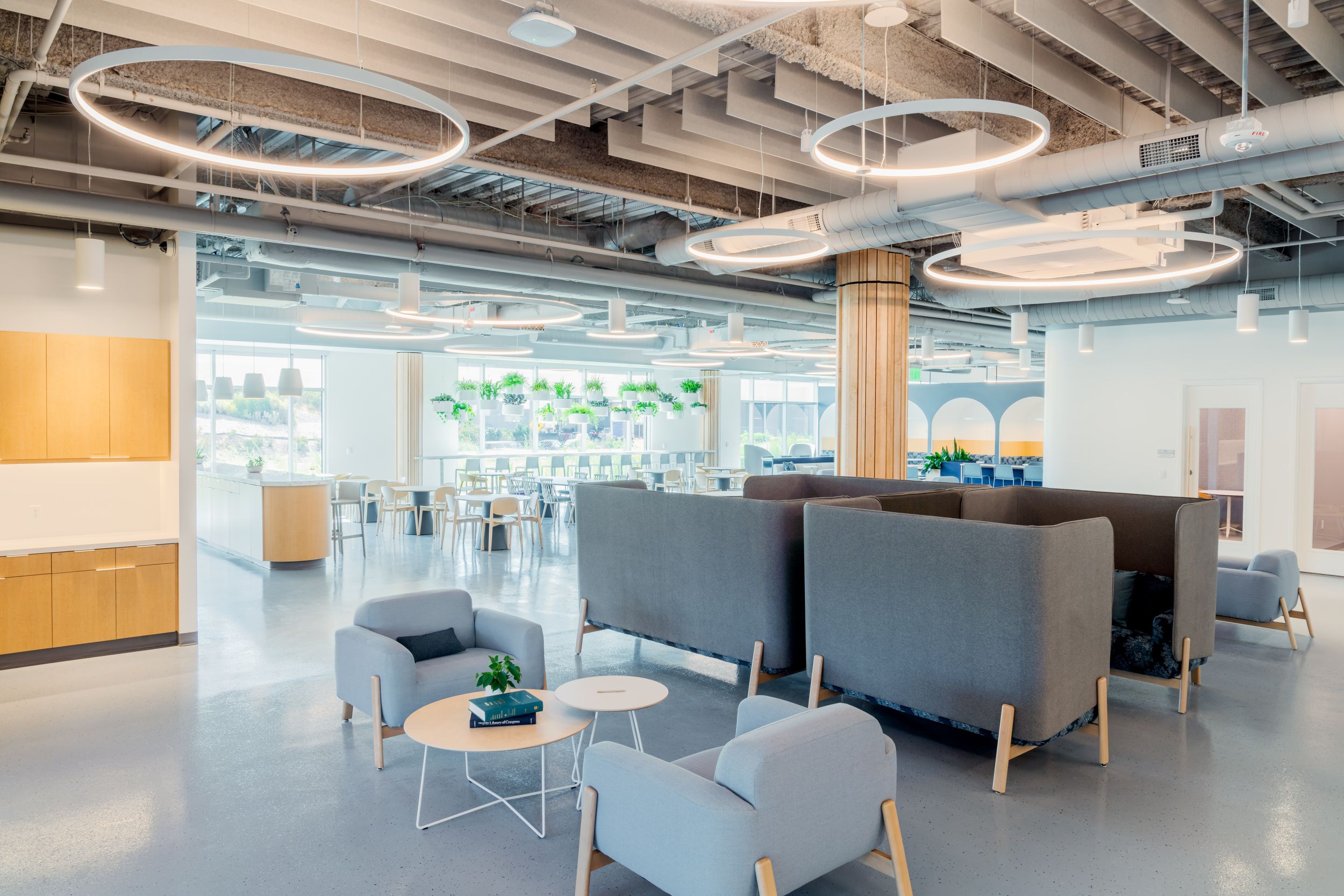 Modern open plan office space with glass walls, exposed ceiling, and collaborative workstations in a contemporary design.