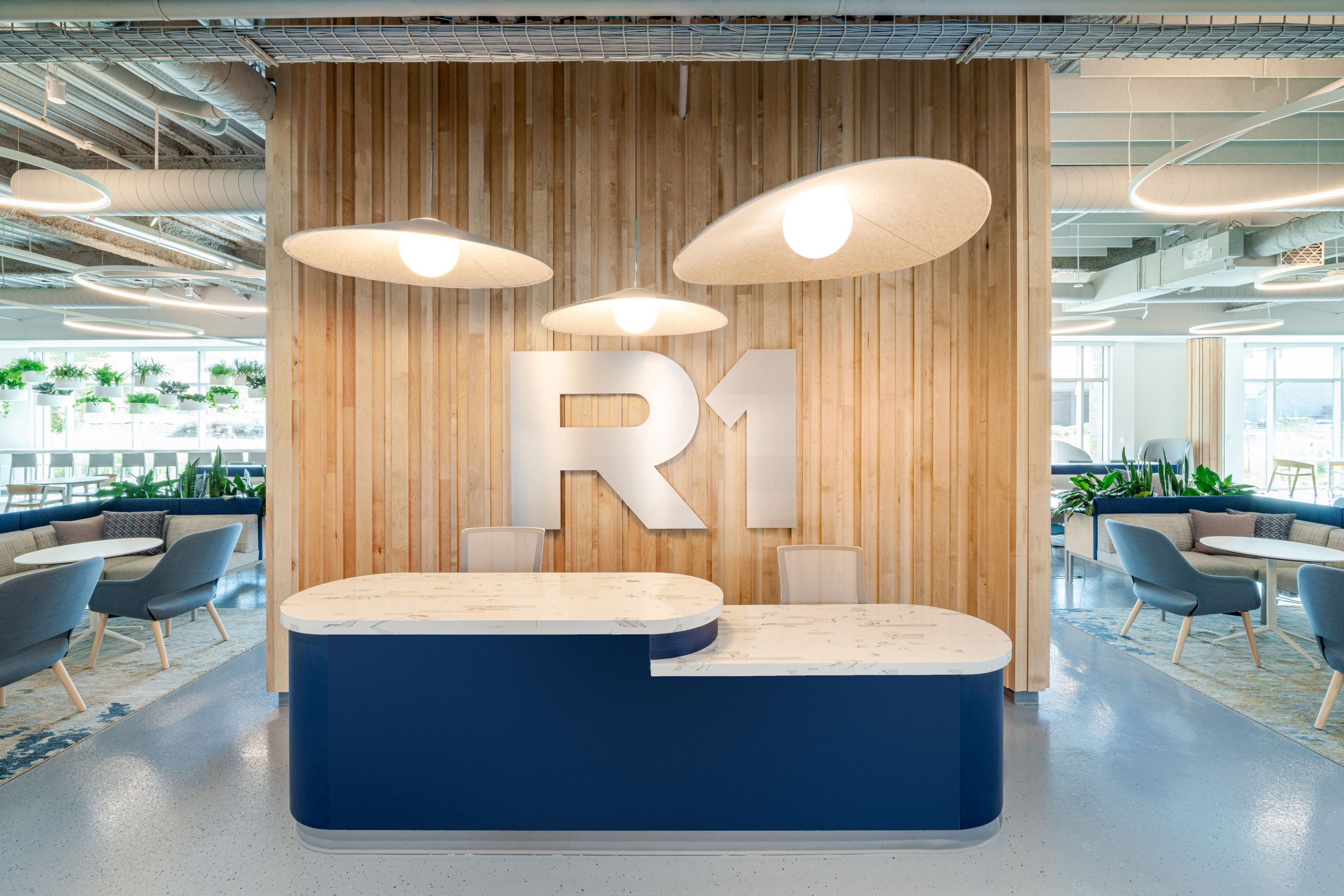Modern office interior with wooden wall paneling, suspended light fixtures, and open workspace design elements.