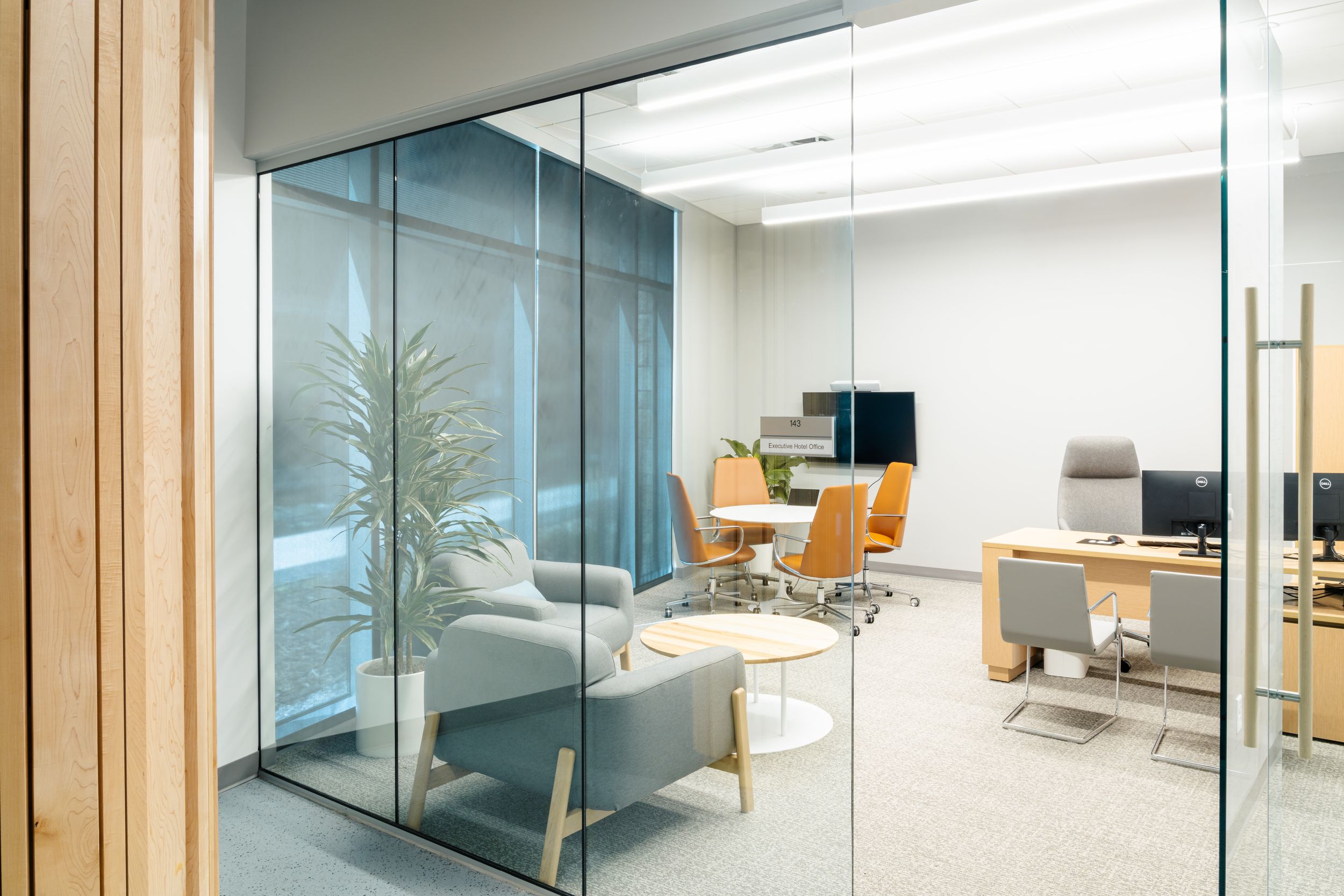 Modern office interior with glass walls showcasing clean minimalist design and natural lighting throughout the space.