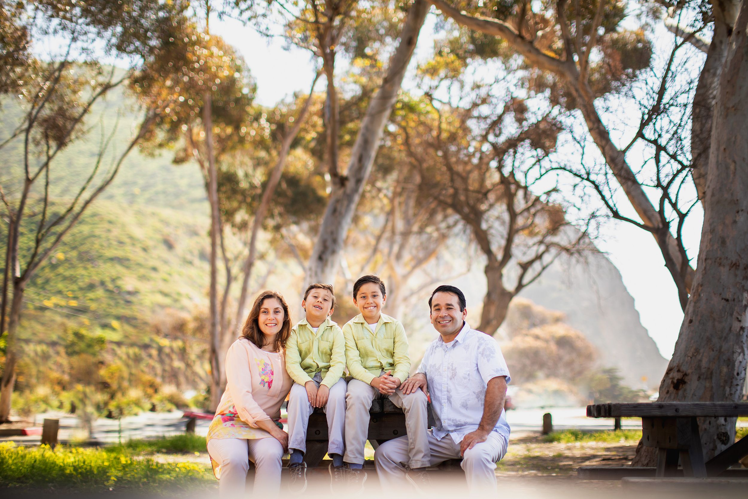 A family relaxes together on a grassy hill during a sunset photoshoot.