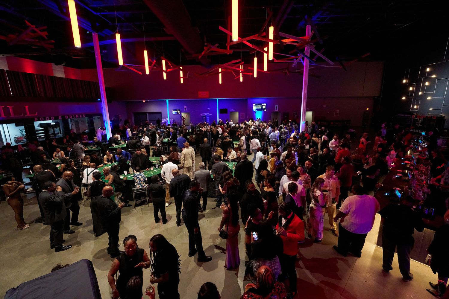 Colorful nightclub atmosphere with bright red and purple lighting illuminating a crowded dance floor at an entertainment venue.