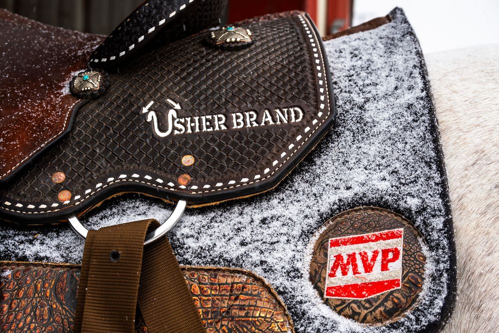 Leather saddle with decorative stitching covered in snow.