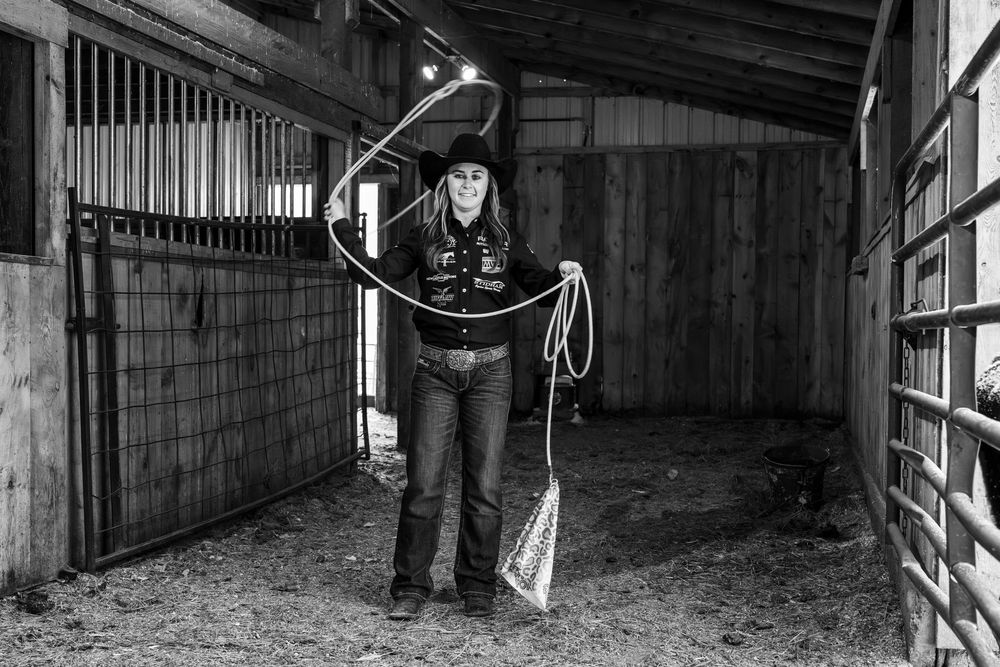 Inside view of a dimly lit horse stable with wooden beams and stalls.
