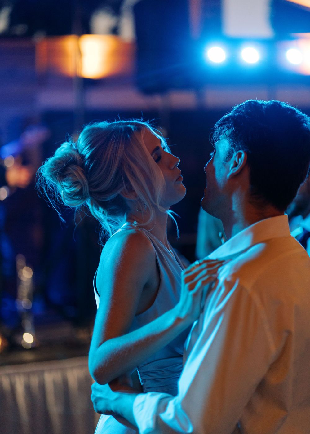 Bride and groom share a romantic dance under blue lights at their wedding reception.