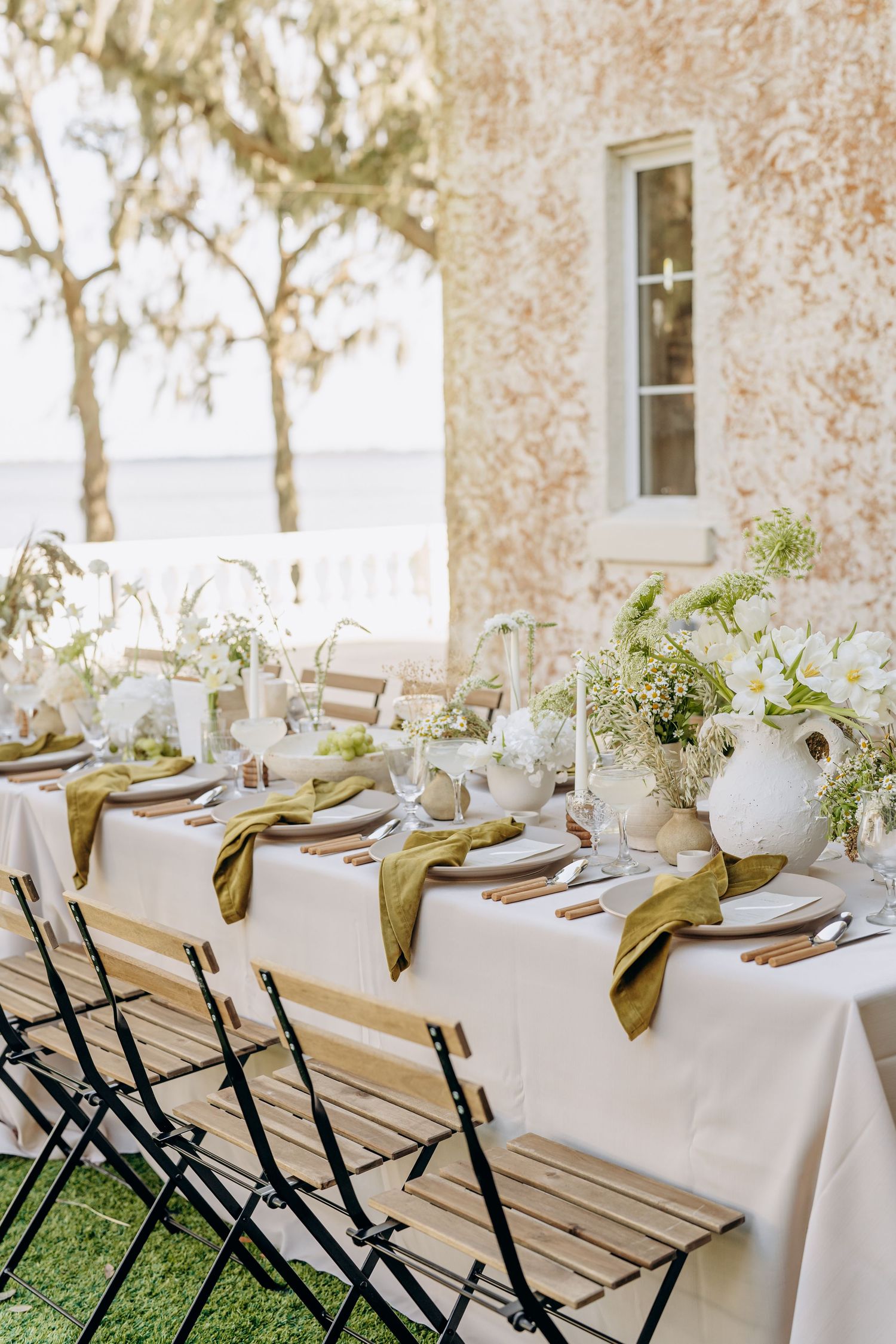 Elegant wedding reception tables set with white linens, gold napkins, and delicate floral centerpieces.
