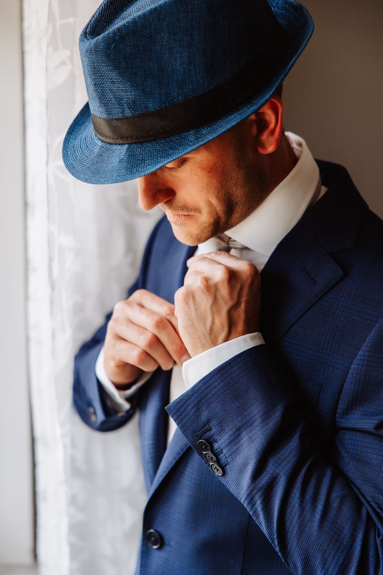 Sequence of photos showing a person in a navy suit and cap looking contemplative near a window.