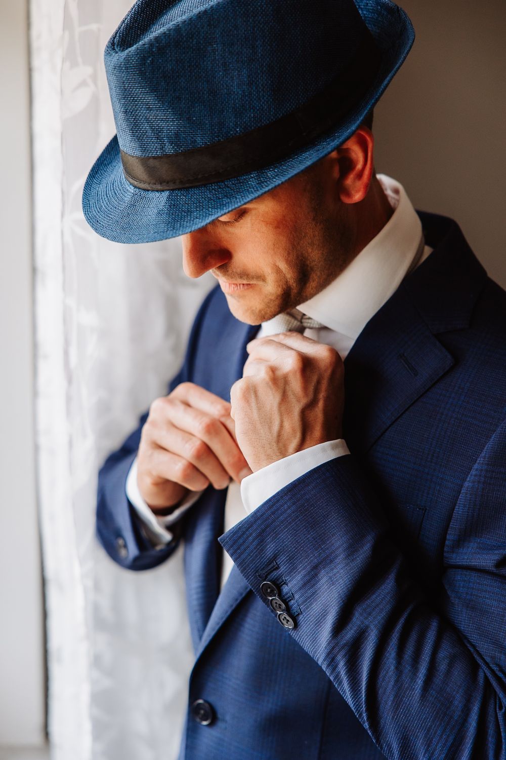 Sequence of photos showing a person in a navy suit and cap looking contemplative near a window.