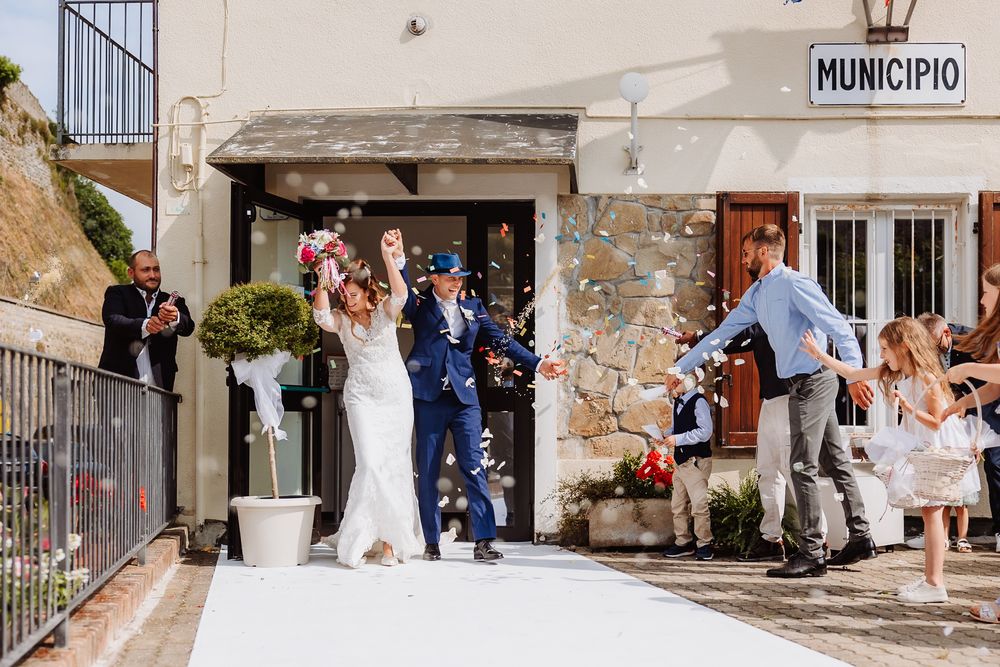 A wedding celebration outside an Italian municipio building with confetti being thrown in celebration during a summer day.