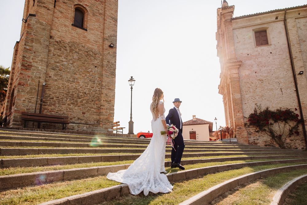 Couple shares a romantic moment on stone steps by an ancient church during their elegant outdoor wedding photoshoot.