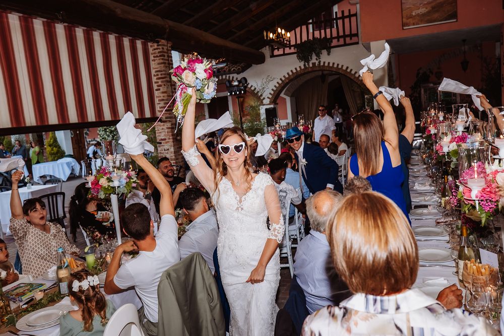 Wedding celebration with guests waving white napkins during reception in rustic venue with striped awning.