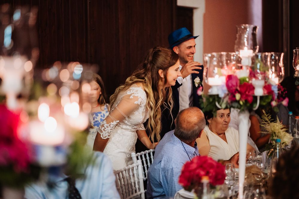 Guests gathered at an elegant wedding reception with candlelit tables decorated with bright pink floral centerpieces.