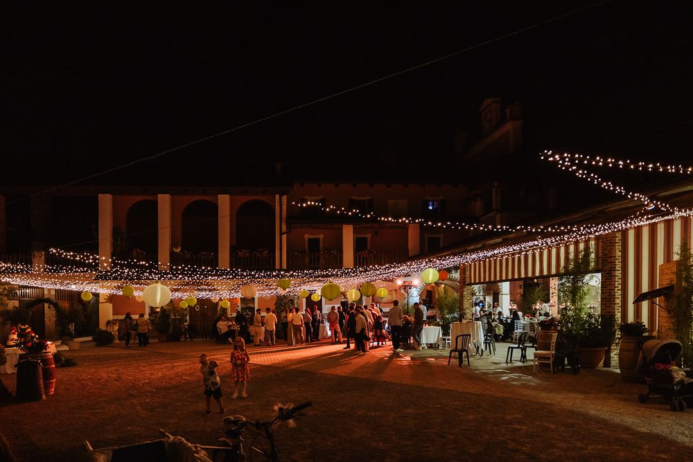 Wedding reception at night with string lights illuminating an outdoor barn venue filled with mingling guests.