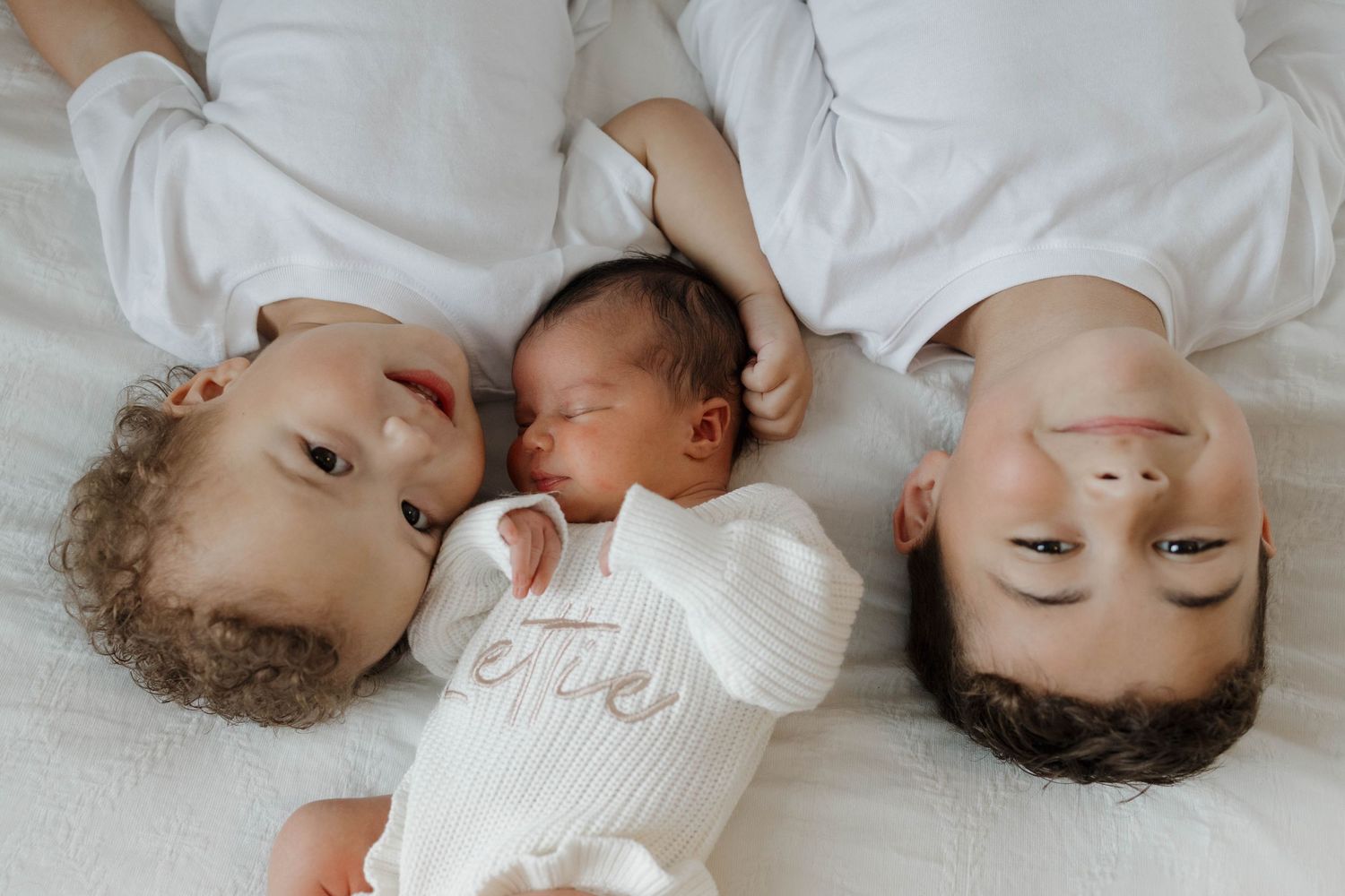 Sleeping baby laying on white bedding in a dreamy, candid photography series.