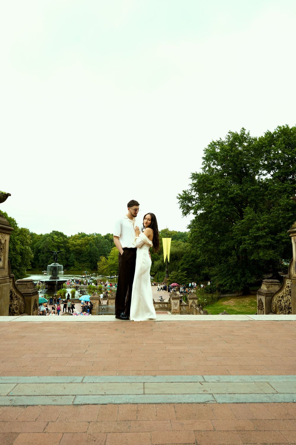 Couple poses on elevated platform overlooking scenic park landscape.