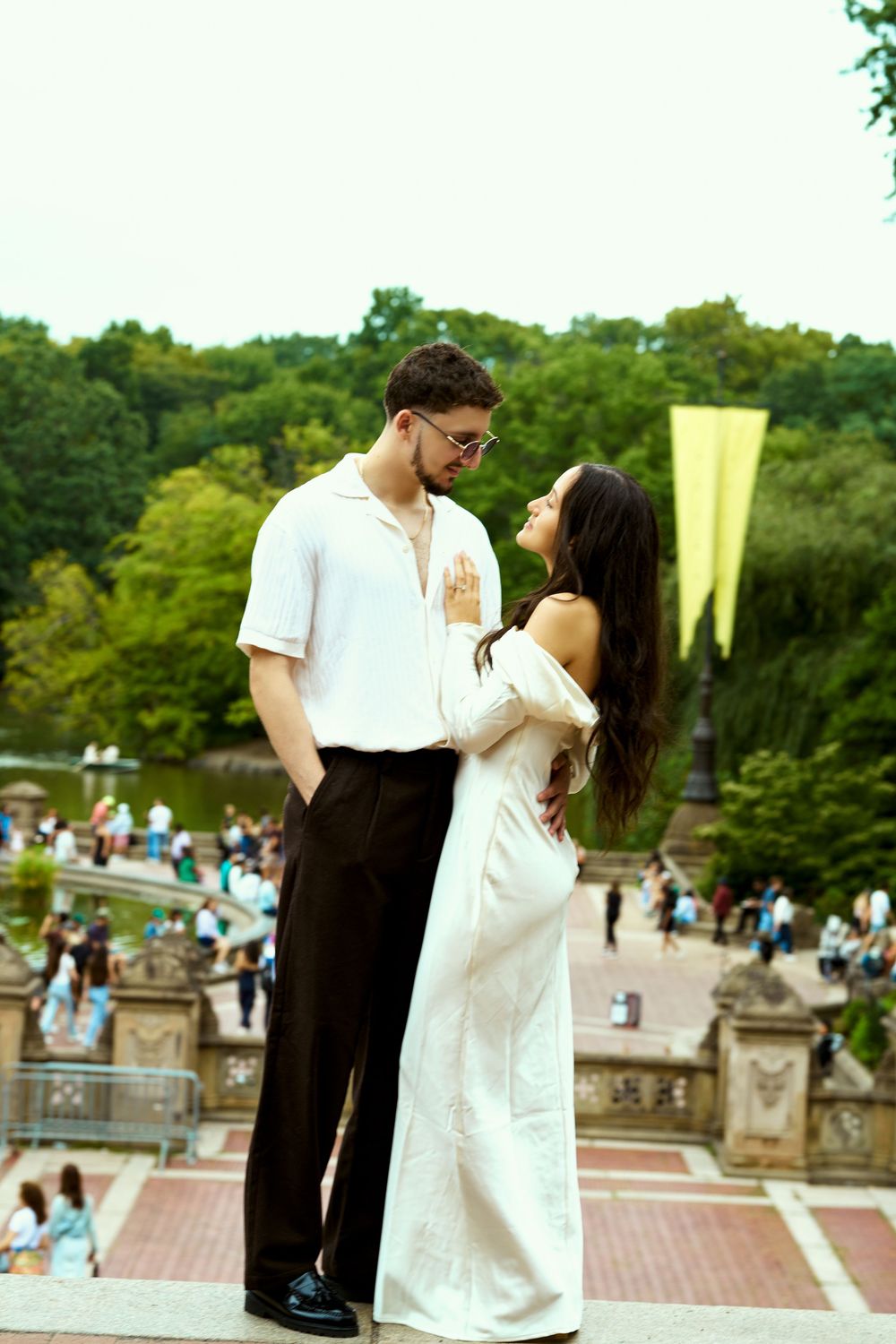 Romantic portrait on historic stone steps with park visitors in background.