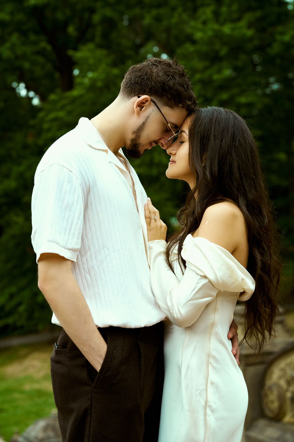 A romantic couple in white clothing sharing an intimate moment outdoors.