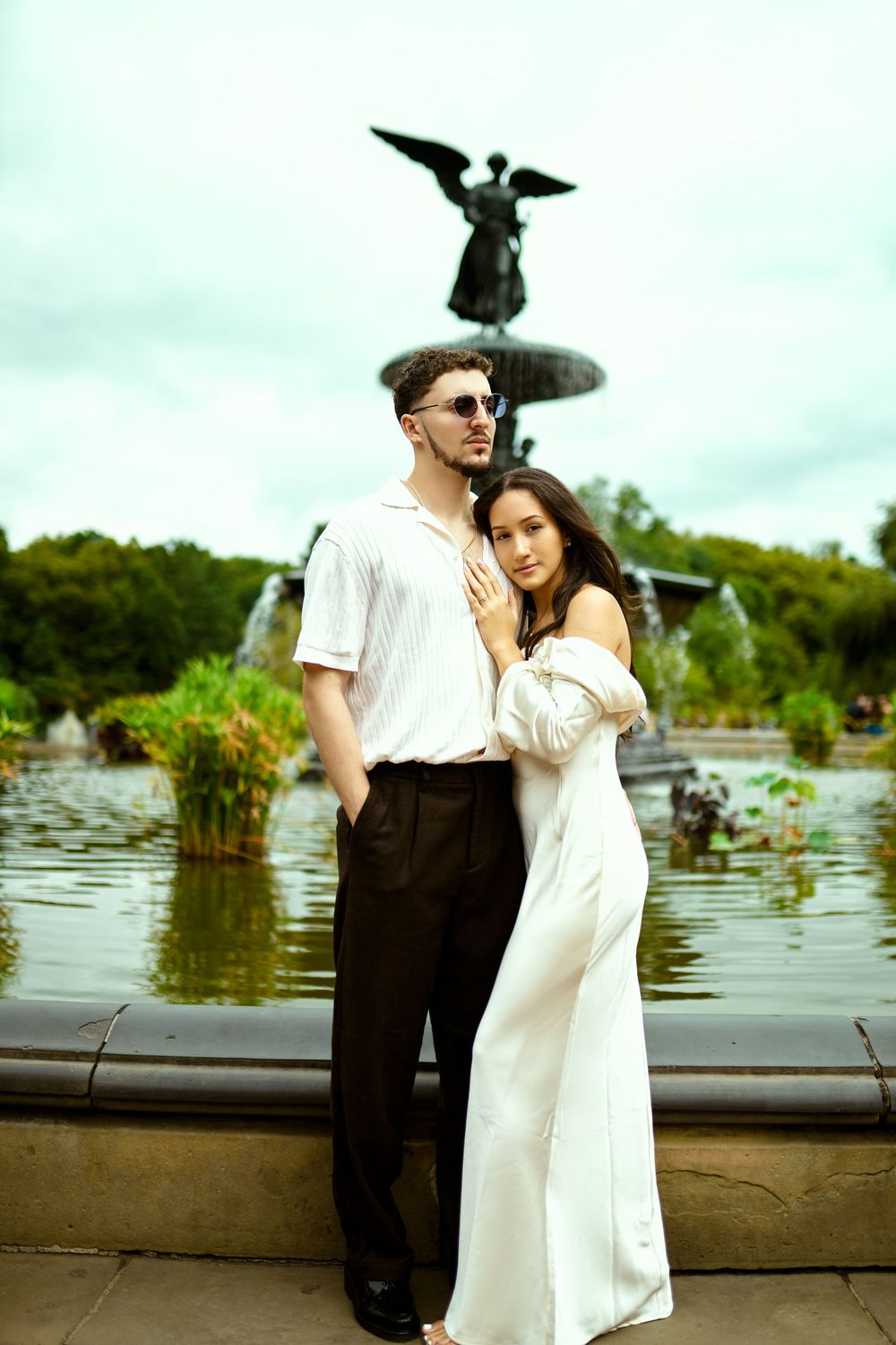 A romantic couple poses by the Bethesda Fountain in white and black attire.