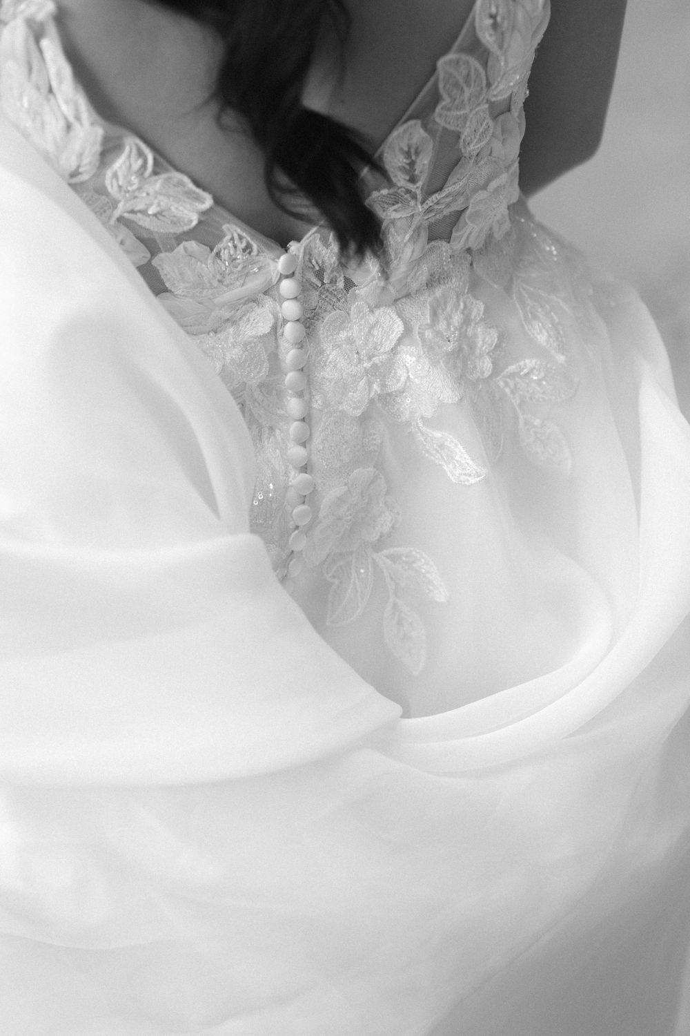 Close-up detail of intricate lace and button details on the back of a white wedding gown.