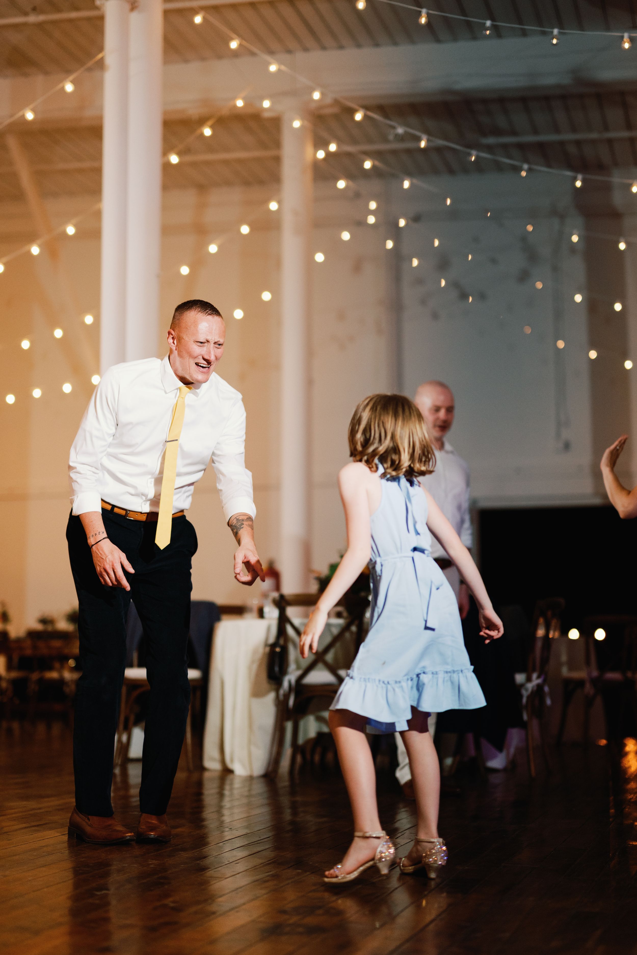 A sequence of dance moves captured in candid photos with warm string lights glowing overhead at an indoor venue.