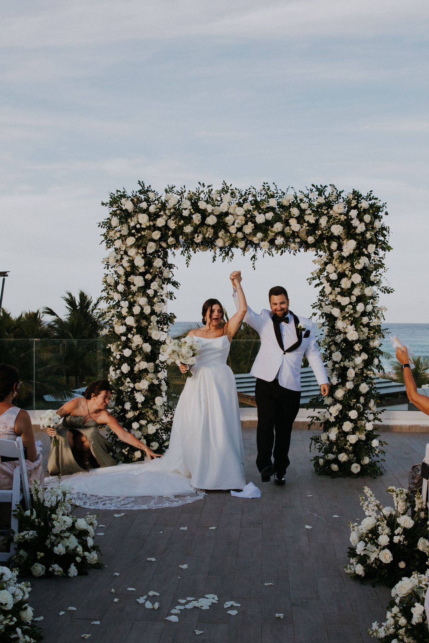 Joyful celebration moments at an outdoor wedding with a stunning floral arch backdrop.