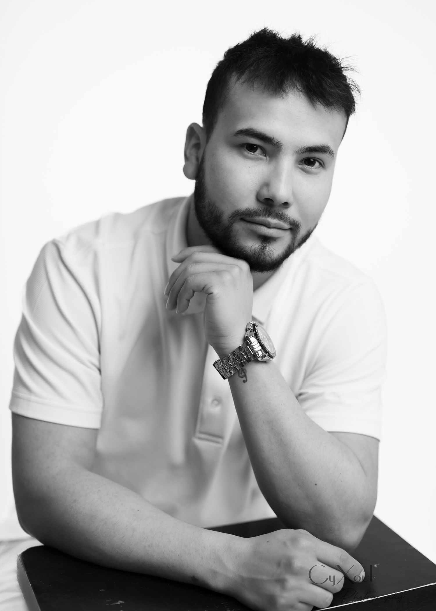 Person in white t-shirt shown in three similar poses leaning on black surface, creating artistic composition.