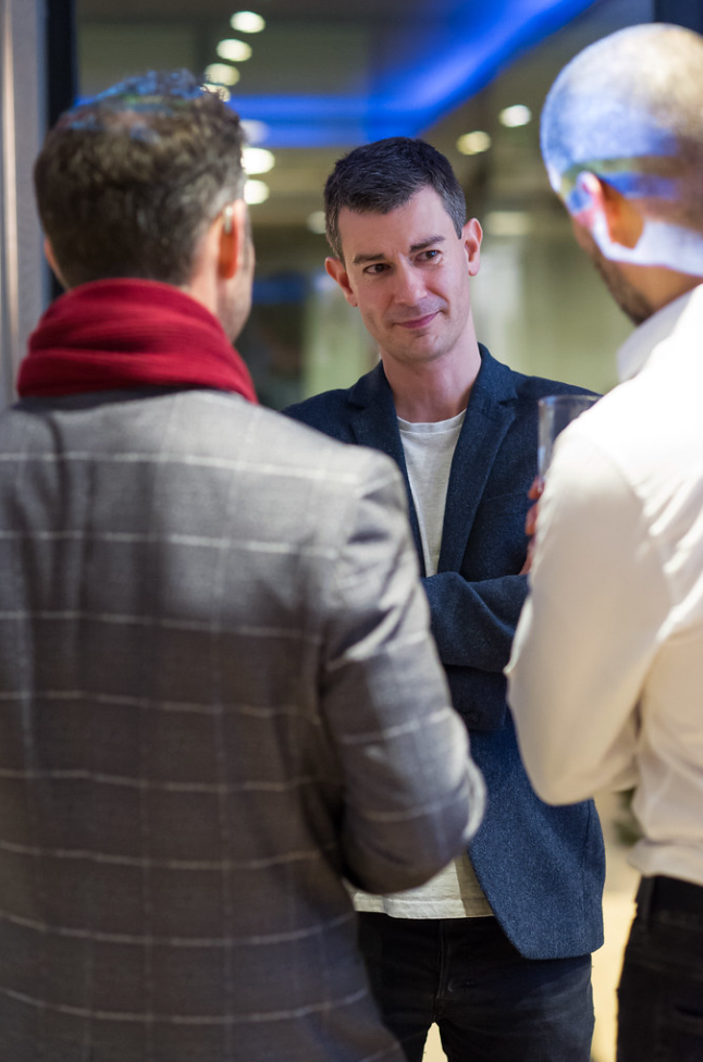 Four sequential images show people in business attire engaged in conversation at what appears to be a networking event.