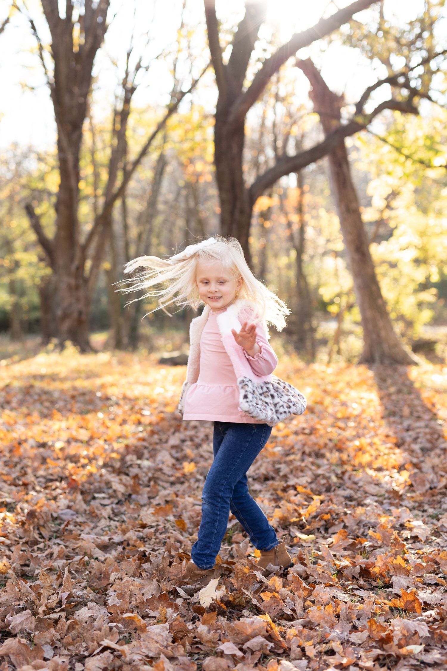 Blonde-haired girl twirling around on a sunny fall evening
