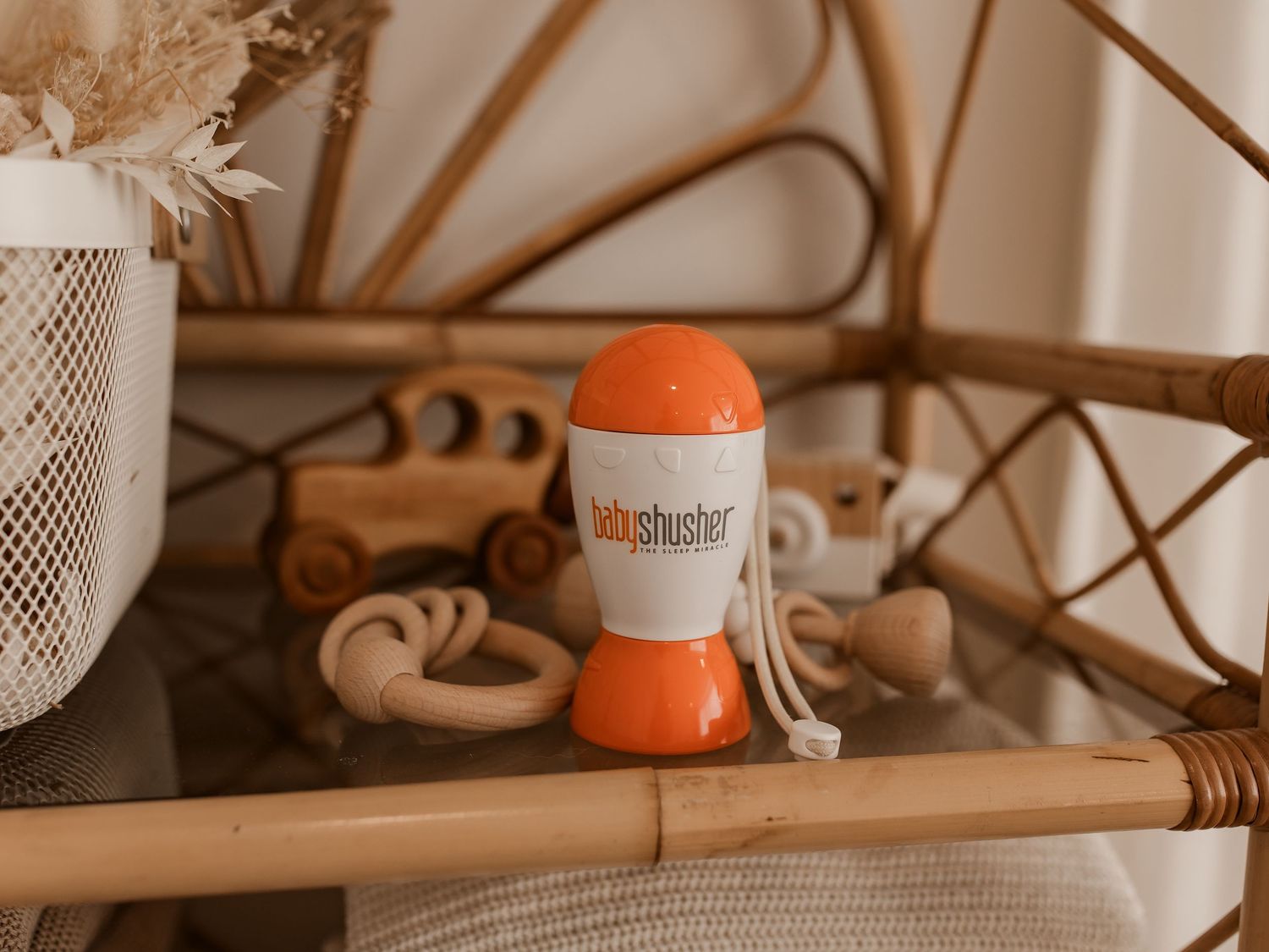An orange and white Tubshroom hair catcher sits on a wooden shelf with dried pampas grass in a vase.