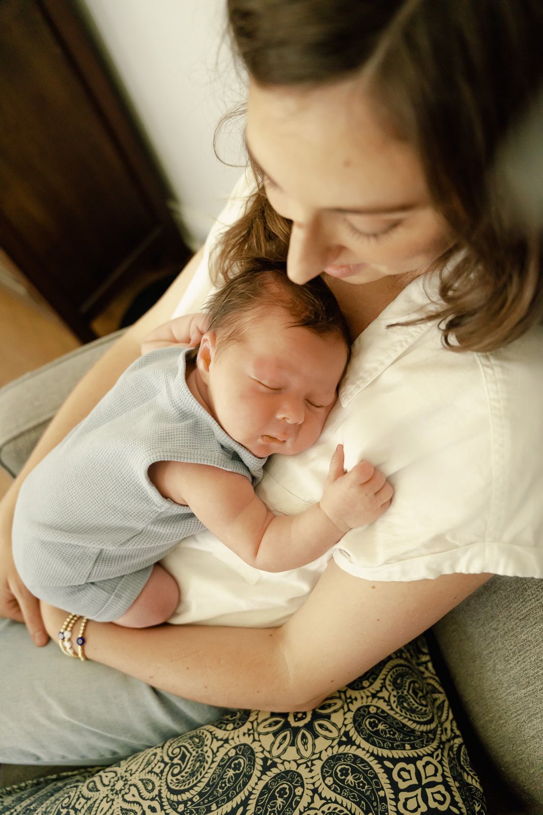 An intimate portrait of a sleeping newborn being cradled in soft lighting while resting against a patterned blanket at newborn session
