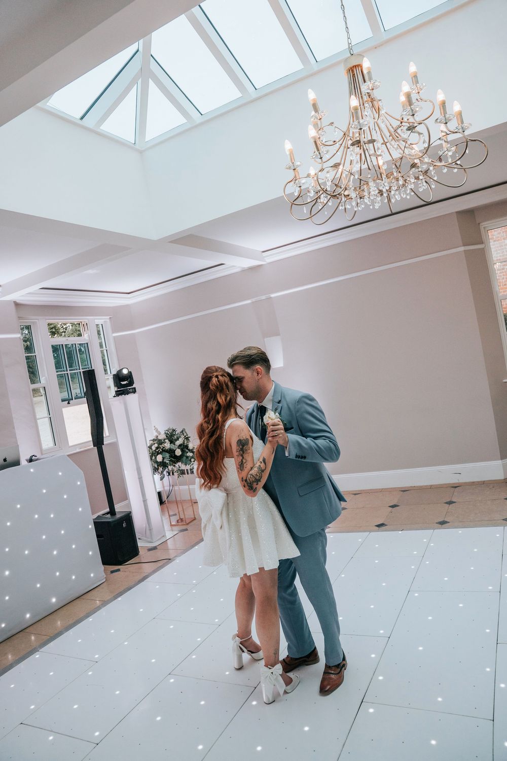 Newlyweds dancing at Rockbeare Manor reception under chandelier